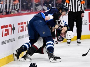 Arizona Coyotes' Connor Mackey (12) and Winnipeg Jets' Morgan Barron (36) fight during the second period in Winnipeg on Tuesday.
