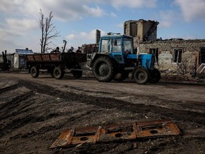 Local residents ride on a tractor along a street in the destroyed village of Topolske, Kharkiv region, on Friday, March 10, 2023, amid Russia's military invasion of Ukraine.