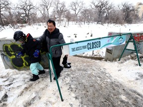 A man leads his son past a sign for the first closure of the season along the Nestaweya River Trail at the Hugo Docks in Winnipeg on Sunday, March 5, 2023.