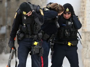 Police officers turn their backs on a residence while the explosive device they threw inside detonates, in 500 block of Furby Street in Winnipeg on Friday, March 10. 2023.