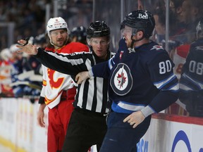 Winnipeg Jets' Pierre-Luc Dubois (right) is separated from a Calgary Flames player.