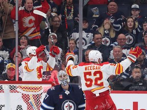 Flames defenceman MacKenzie Weegar (52) celebrates the Calgary Flames first goal in front of Jets goalie Connor Hellebuyck Wednesday night.