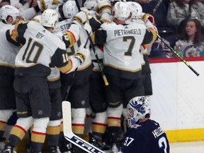 Connor Hellebuyck (37) of the Winnipeg Jets skates off as members of the Vegas Golden Knights celebrate victory in the second overtime period of Game 3 of the First Round of the 2023 Stanley Cup Playoffs on April 22, 2023 at Canada Life Centre in Winnipeg.