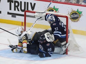 Chander Stephenson of the Golden Knights and Pierre-Luc Dubois of the Jets crash into Jets goalie Connor Hellebuyck during Game 4 on Monday.