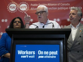 Public Service Alliance of Canada National Executive Vice-President Sharon DeSousa (left) and Quebec Regional Executive Vice-President Yvon Barriere look on as National President Chris Aylward makes a point during a news conference at union headquarters, Monday, April 17, 2023 in Ottawa.