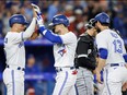 Cavan Biggio, centre, of the Toronto Blue Jays celebrates at the plate with Whit Merrifield, left, and Brandon Belt after Biggio hit a three-run home run in the fourth inning of their MLB game against the Chicago White Sox at Rogers Centre on April 24, 2023 in Toronto.