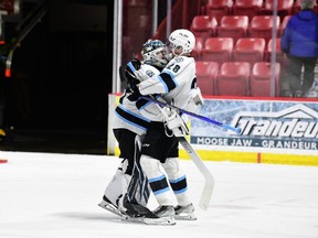 Connor Geekie of the Winnipeg Ice (right) celebrates with goalie Daniel Hauser after their team eliminated the Moose Jaw Warriors in the WHL playoffs on Monday.