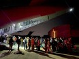 Spanish diplomatic personnel and citizens queue outside a military plane after they were evacuated from Sudan in Djibouti, April 24, 2023.