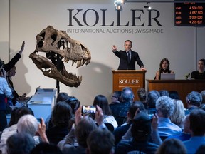 Koller auction house director Cyril Koller (centre) gestures next to the skull of the 'Trinity' during sale of the skeleton of the Tyrannosaurus-Rex (T-Rex) by Koller auction house in Zurich on April 18, 2023.