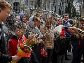 An Orthodox priest sprays holy water on believers after a service which marks the Orthodox feast of Palm Sunday, amid Russia's invasion of Ukraine, in Kyiv, Ukraine April 9, 2023.