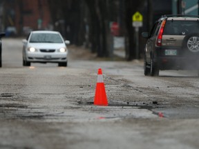 A pothole with a traffic cone in it on a Winnipeg street