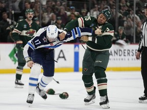Winnipeg Jets center Adam Lowry, left, and Minnesota Wild right wing Ryan Reaves fight during the third period of an NHL hockey game, Tuesday, April 11, 2023, in St. Paul, Minn.