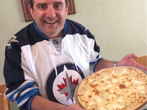 Pasquale's Restaurant owner Joe Loschiavo holds his Winnipeg restaurant's new hockey-themed creation in honour of the Winnipeg Jets playing in the NHL playoffs. Pasquale's Whiteout Pizza is loaded with several cheeses ... buffalo mozzarella, ricotta, provolone and grana padano. The crust is topped with garlic alfredo sauce.