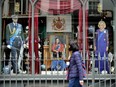 A woman walks by a storefront featuring King Charles III in London on Tuesday, May 2, 2023. Crowds from all over the world -- including Canada -- were beginning to gather in London ahead of the coronation of King Charles.