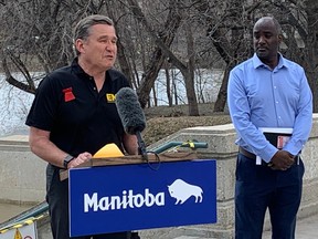 Manitoba Transportation and Infrastructure Minister Doyle Piwniuk addresses the media to give a flood update to the media alongside the swollen Assiniboine River at the Manitoba Legislature in Winnipeg as Fisaha Unduche, executive director, hydrologic forecasting and water management, Manitoba Transportation and Infrastructure, listens on Friday, May 5, 2023.