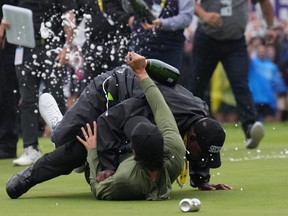 Canadian professional golfer Adam Hadwin, bottom, is stopped by a security guard while he tries to celebrates with Nick Taylor, of Canada, after Taylor won the Canadian Open championship on the fourth playoff hole on Sunday.