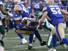 Winnipeg Blue Bombers' Matt Cole (6) is taken down by Saskatchewan Roughriders' Nelson Lokombo (21) during first half CFL action in Winnipeg Friday, June 2, 2022.