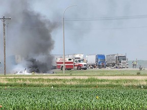 Smoke comes out of a vehicle as first responders converge on a collision that left 15 dead near Carberry, west of Winnipeg on Thursday, June 15, 2023. (Photo by Nirmesh VADERA / AFP)