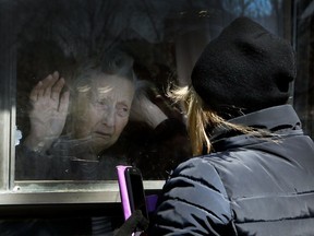 A woman visits her 86-year-old mother through a window at the Orchard Villa long-term care home in Pickering, Ont., during the COVID-19 pandemic in 2020.
