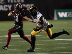 Hamilton Tiger-Cats linebacker Simoni Lawrence pushes Ottawa Redblacks quarterback Dustin Crum out of bounds as he runs the ball during the first half of a CFL game on July 28, 2023 in Ottawa.