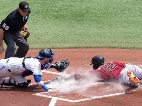 Arizona Diamondbacks' Lourdes Gurriel Jr. slides safe to home as Blue Jays catcher Danny Jansen can't complete the tag during the first inning in Toronto, Sunday, July 16, 2023.