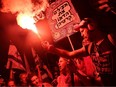 A protester carries a flare during a demonstration against the Israeli government's judicial reform plan in Tel Aviv on July 27, 2023.