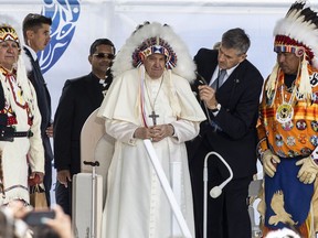 Pope Francis receives a traditional headdress after apologizing for the Roman Catholic Church's role in the residential school system, in Maskwacis, Alta., during his papal visit across Canada on Monday, July 25, 2022.