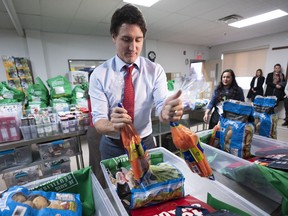 Prime Minister Justin Trudeau loads food baskets at a food bank in Montreal, on Tuesday, December 20, 2022.