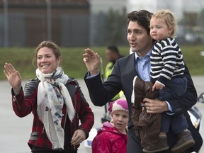 Prime Minister Justin Trudeau and his wife Sophie Gregoire Trudeau wave to the media with their children Hadrien and Ella-Grace as they board a government plane on Thursday Nov. 26, 2015, in Luton, England.