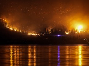 The McDougall Creek wildfire burns on the mountainside above lakefront homes, in West Kelowna, B.C., on Friday, Aug. 18, 2023.