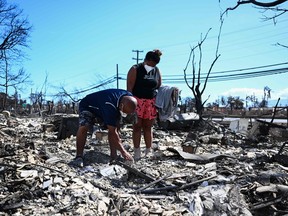 Davilynn Severson and Hano Ganer look for belongings in the ashes of their family's home in the aftermath of a wildfire in Lahaina, western Maui, Hawaii on August 11, 2023.