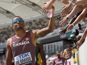 Andre De Grasse, of Canada, receives high fives from fans during the men's 200-meter heat at the World Athletics Championships in Budapest, Hungary, Wednesday, Aug. 23, 2023.