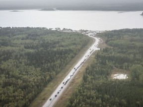 Vehicles line up for fuel at Fort Providence, N.W.T., on the only road south from Yellowknife, Thursday, Aug. 17, 2023.