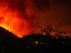 The McDougall Creek wildfire burns on the mountainside above houses in West Kelowna, B.C., on Friday, August 18, 2023.