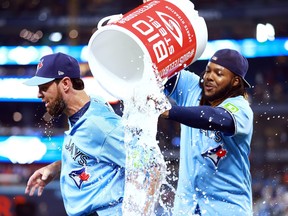 Brandon Belt of the Toronto Blue Jays ducks out of the way as Vladimir Guerrero Jr. tries to douse him with water.
