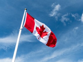 Canada Flag Waving in the Wind Against Blue Sky Background