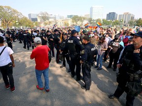 Police stand between competing protesters outside the Manitoba Legislative Building