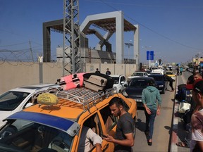 Palestinians with foreign passports arrive at the Rafah gate hoping to cross into Egypt as Israel's attacks on the Gaza Strip continues on Oct. 14, 2023.