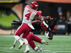 B.C. Lions' Jevon Cottoy is upended by Calgary Stampeders' Cameron Judge and Jonathan Moxey, back, after making a reception during the first half of a CFL football game, in Vancouver.