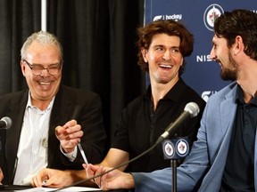 Jets teammates Mark Scheifele (centre) and Connor Hellebuyck (right) laugh after signing contracts with general manager Kevin Cheveldayoff at Hockey For All Centre yesterday.   KEVIN KING/Winnipeg Sun
