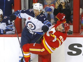 Jets defenceman Brenden Dillon lays out Flames forward Dillon Dube during Wednesday's season opener in Calgary.