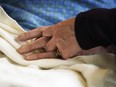 A patient has his hand held at a hospital, in Minneapolis, May 3, 2021.