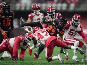 B.C. Lions' JaQuan Hardy is hit by Calgary Stampeders' Brad Muhammad as he carries the ball during the first half of game in Vancouver on Oct. 20, 2023.