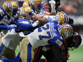 Winnipeg Blue Bombers' Johnny Augustine tackles B.C. Lions' Terry Williams, right, as he returns the opening kickoff.
