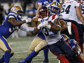 Winnipeg Blue Bombers' Kyrie Wilson (centre back) tackles Montreal Alouettes' William Stanback.