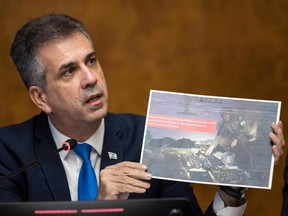Israel Foreign Minister Eli Cohen shows an image of an Israeli soldier posing next to a weapons cache, which was allegedly found at the Rantisi Hospital in Gaza according to the Israeli army, as he speaks in a press conference at the European Office of the United Nations, Palais des Nation, in Geneva, Tuesday, Nov. 14, 2023.