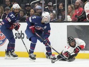 Canada forward Laura Stacey (right) reaches for the puck while defended by U.S. defender Megan Keller (centre) during the second period of a rivalry series game in Los Angeles, Saturday, Nov. 11, 2023.