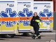 A paramedic walks past parked ambulances