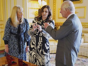 King Charles is presented with the first struck '5 Coronation coin by Royal Mint CEO Anne Jessopp, left, and director Rebecca Morgan, centre, at Windsor Castle, Berkshire, Thursday, April 13, 2023. The first Canadian coins bearing the face of the King are soon to be circulated across the country.