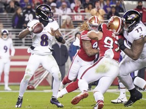 Lamar Jackson, left, of the Baltimore Ravens attempts a pass against the San Francisco 49ers during the fourth quarter at Levi's Stadium on Dec. 25, 2023 in Santa Clara, Calif.